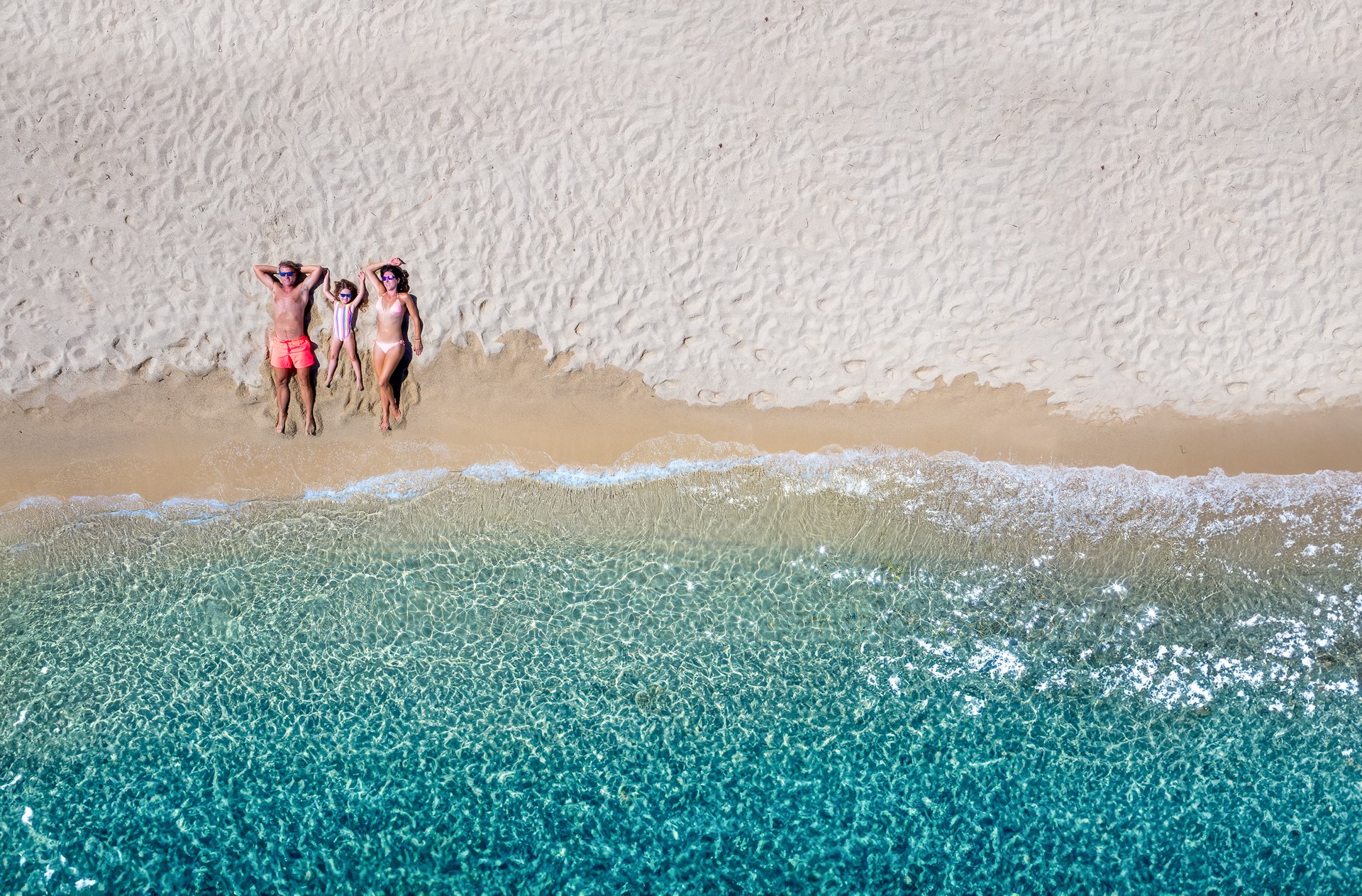 Summer holiday concept with a happy family lying on a beautiful beach